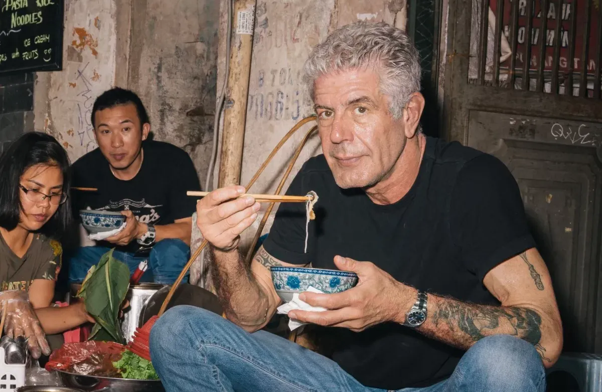 Fotografia dello chef Anthony Bourdain mentre mangia. Vita bohémien, chef-artista.