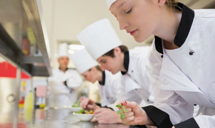 Brigata di cucina durante l'impiattamento in stagione HoReCa.