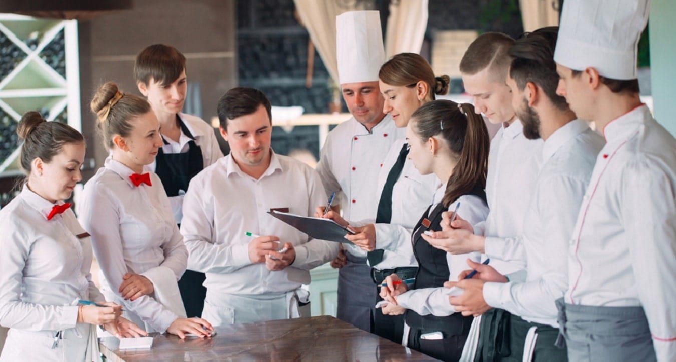 Staff di un ristorante/hotel di lusso in riunione prima del servizio in stagione.