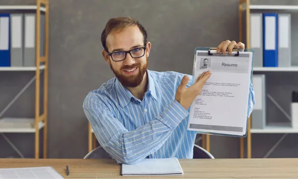 Uomo sorridente che mostra il proprio curriculum vitae